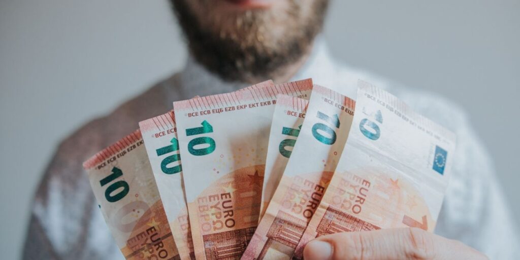 Ein Mann hält mehrere 10-Euro-Scheine