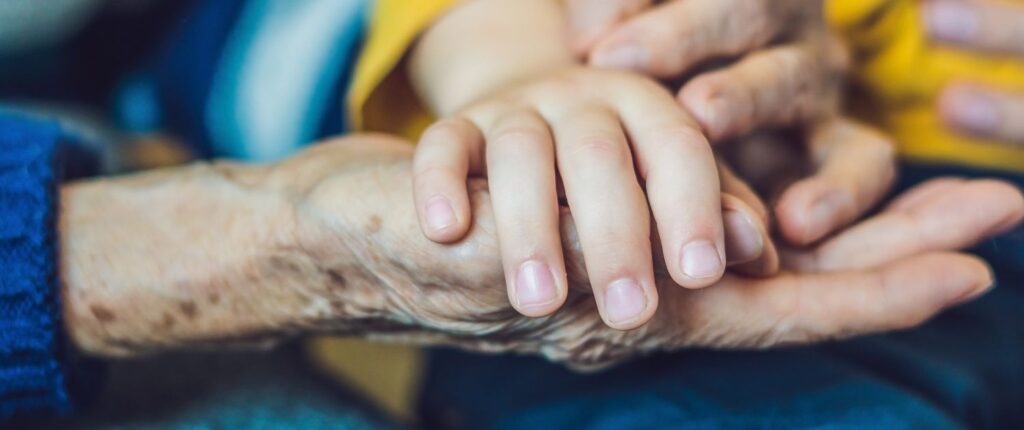 Eine Kinderhand liegt in der Hand eines sehr alten Menschen