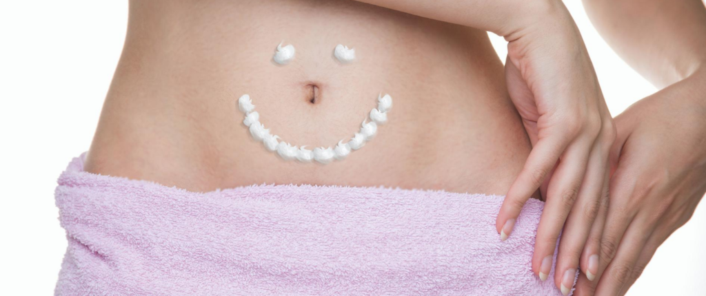 Glücklicher Bauch ohne Verstopfung. Ein aus Body Lotion gemalter Smiley auf einem Bauch.