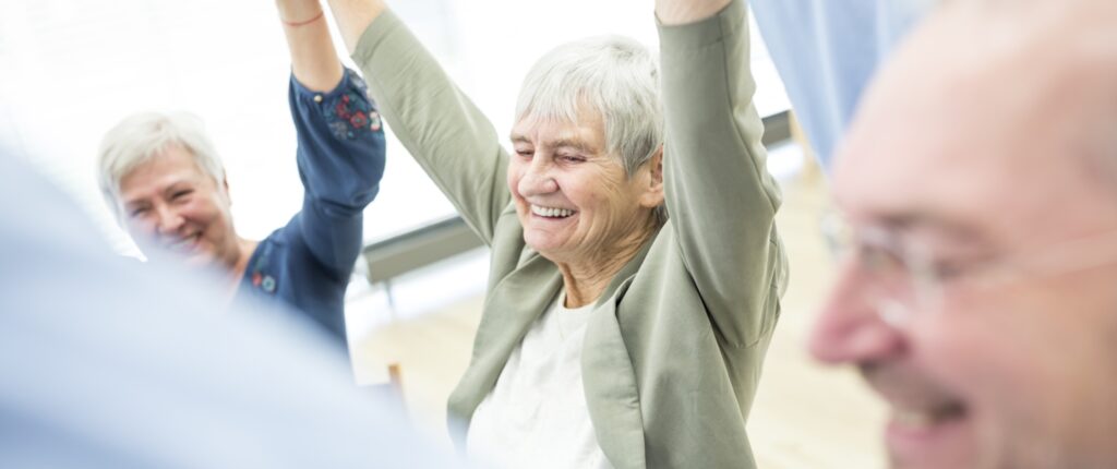 Senioren lachen gemeinsam in der Reha nach Schlaganfall