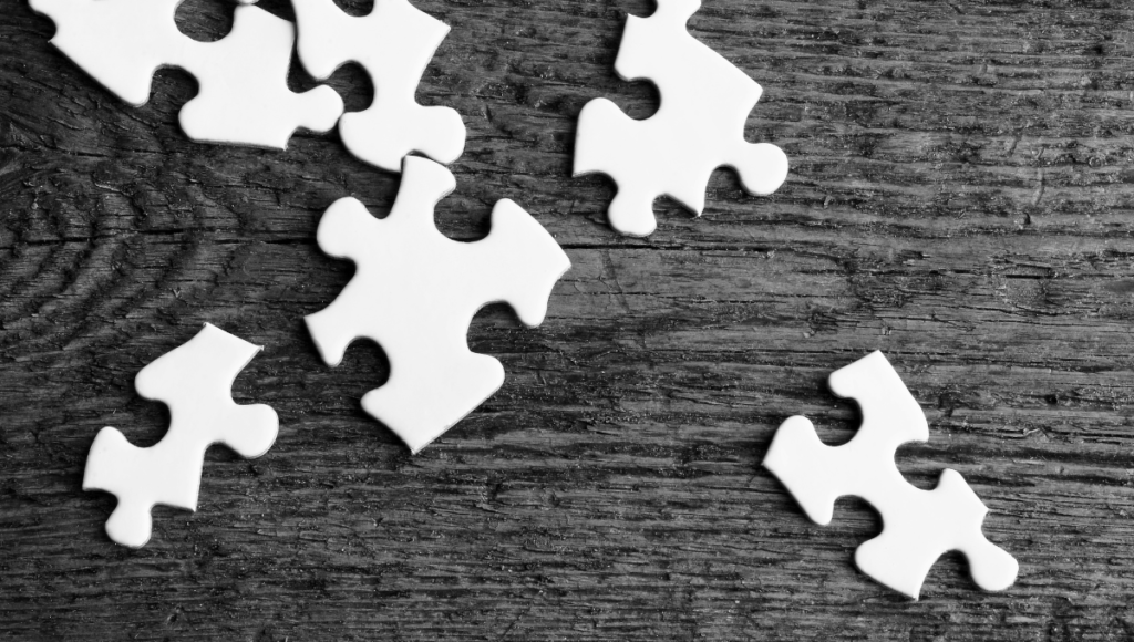 Nicht zusammenpassende Puzzleteile liegen auf einem Holztisch
