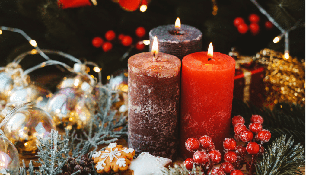 Drei brennende Advents-Kerzen stehen auf einem weihnachtlich geschmückten Tisch.