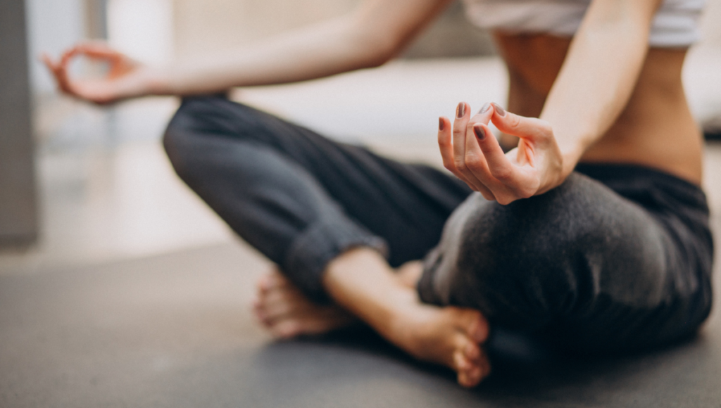 Yoga: Junge Frau sitzt im Lotussitz auf dem Fußboden.