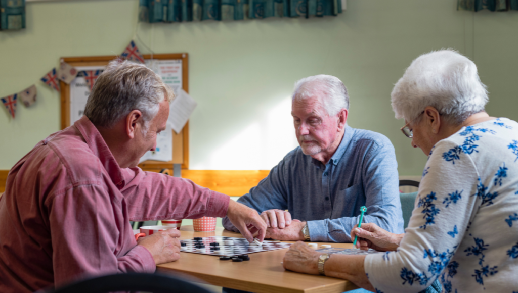 Nachbarschaftshilfe: Zwei Männer spielen am Tisch sitzend eine Partie Dame