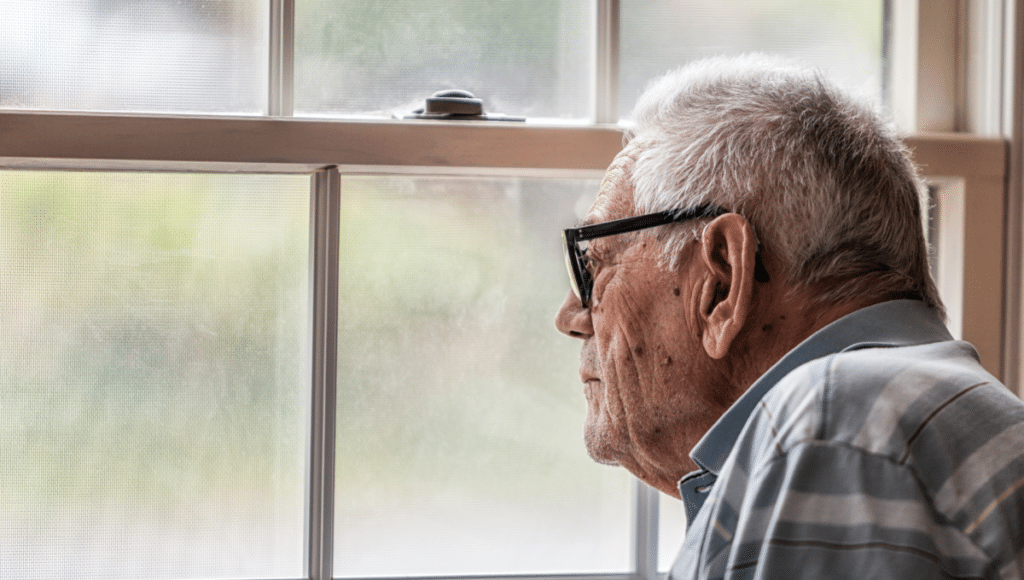 Ein Mann, der an Demenz erkrankt ist, starrt aus dem Fenster.