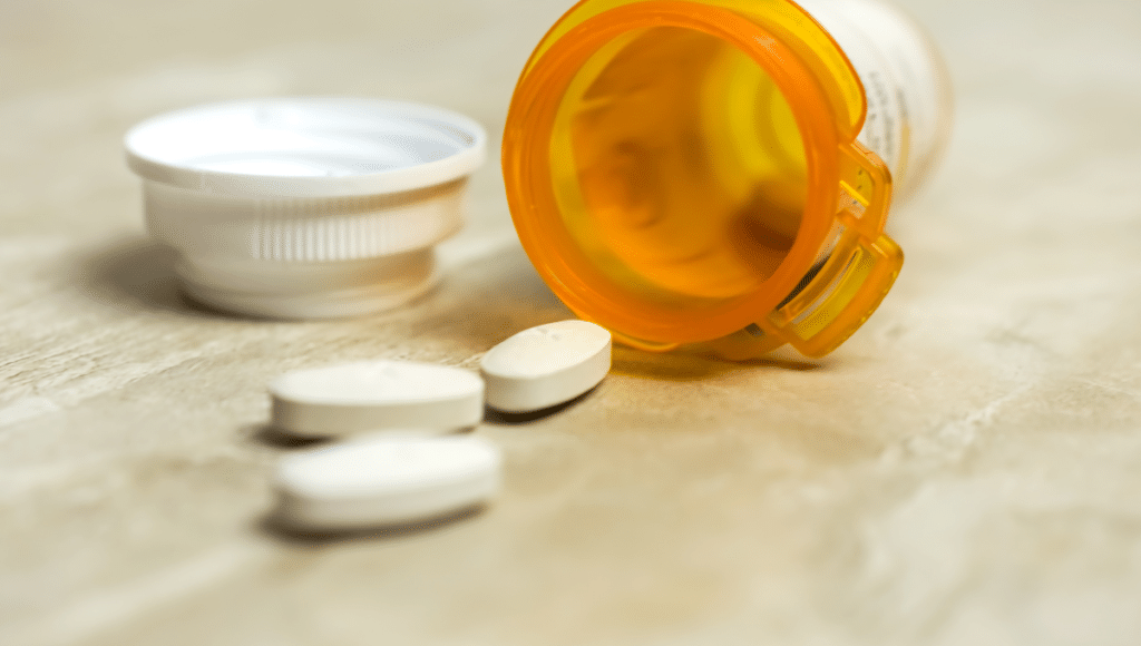 Antibiotika gegen Bakterien: Ein oranges Plastikfläschchen und drei herausgeschüttete Tabletten.