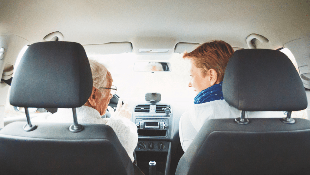 Eine Tochter begleitet ihren alten Vater auf dem Beifahrersitz beim Autofahren