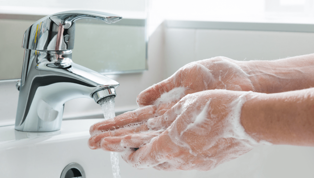 Die eingeseiften Hände werden unter fließendem Wasser gewaschen.