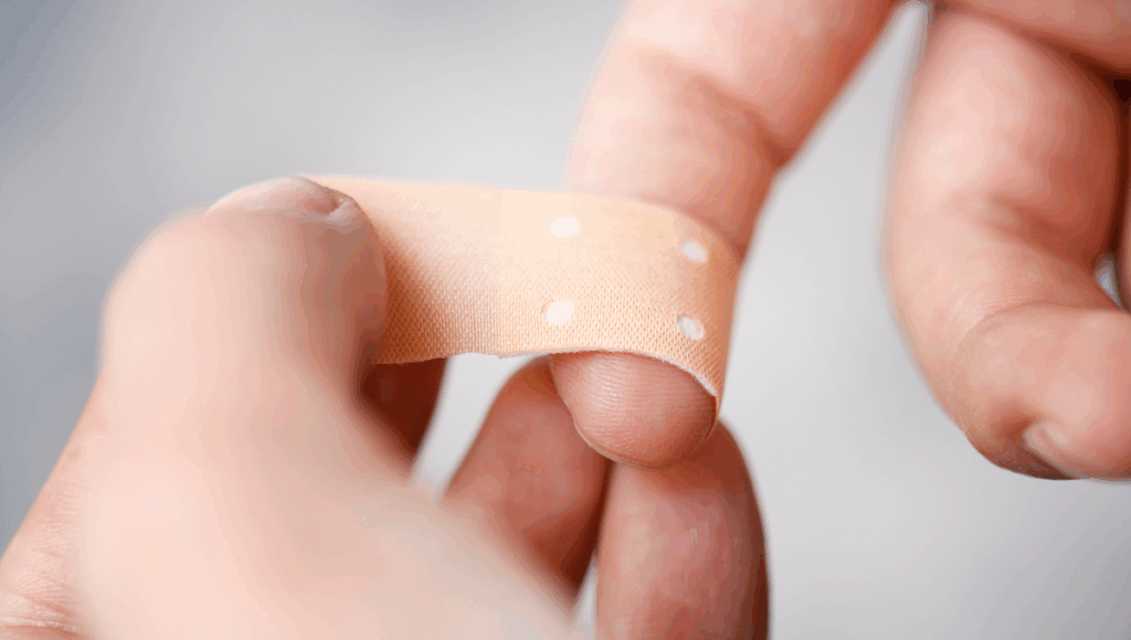 Eine akute Wunde am Finger wird von einem Pflaster überdeckt.